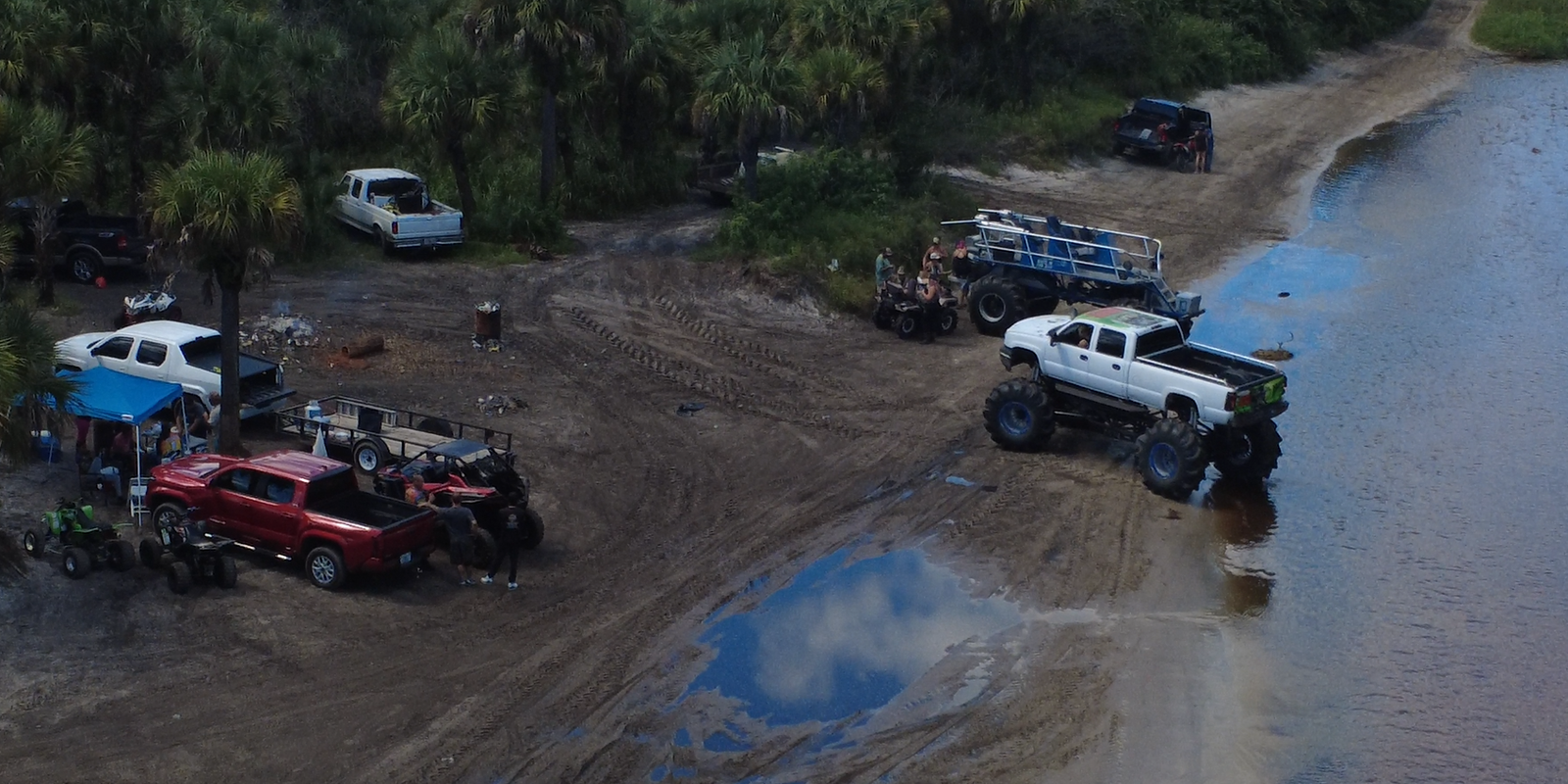 Lifted off-road trucks gathered at the edge of the water